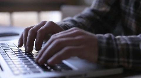 A man sits at a table in a cafe with a laptop, writing text, printing, typing. Stock Footage 59121032