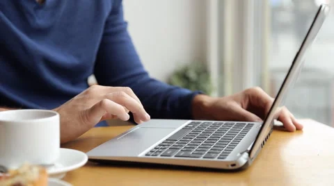 A man sits at a table in a cafe with a laptop, laptop, writing text, printing Stock Footage 67862948