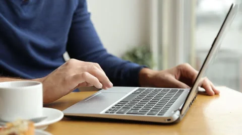 A man sits at a table in a cafe with a laptop, laptop, writing text, printing Stock Footage 67862963