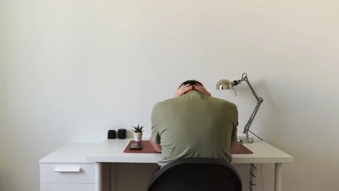 A man sits at a table at home by a computer, clutches his head, thinks, upset Stock Footage 156905524