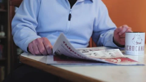 The man sits at a table in the kitchen, reads a newspaper and drinks coffee Stock Footage 170196207