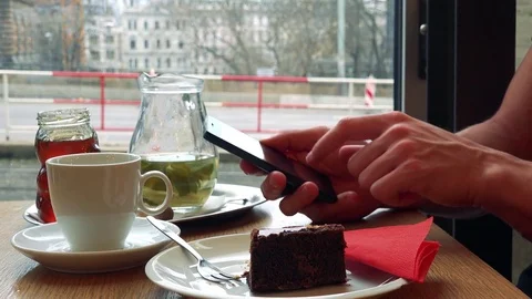 A man sits at a table with meal in a cafe and works on a smartphone - closeup Stock-Footage 75411072