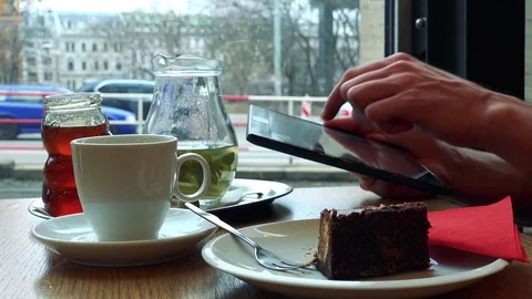 A man sits at a table with meal in a cafe and works on a tablet - closeup from Stock Footage 75411257