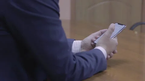 A man sits at a table with a mobile phone Stock Footage 221491156