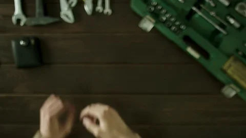 A man sits at a table near the tools are and pulls out money from his wallet Stock Footage 82065482