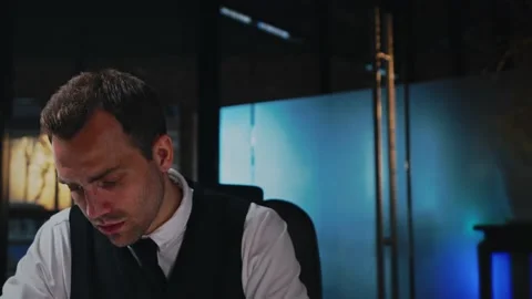 A man sits at a table in the office, works with a computer and documents Stock Footage 201284335