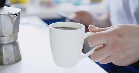 Man sits at table with smartphone and drinks fresh hot drink Vídeo Stock 105501019