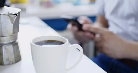 Man sits at table with smartphone and drinks fresh hot drink Vídeo Stock 105501080