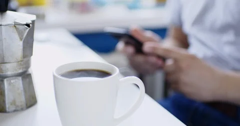Man sits at table with smartphone and drinks fresh hot drink Video stock 105501318