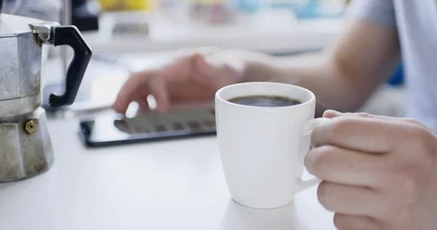 Man sits at table with smartphone and drinks fresh hot drink Vídeo Stock 105501415