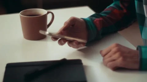 A man sits at a table with a smartphone in his hand 스톡 동영상 106719180