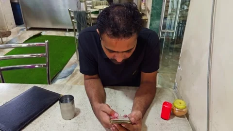 Man sits at table smiling and looking phone Stock Footage 299785550