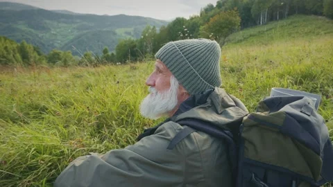 A Man Sits on Top of a Hill Against a Background of Mountains Stock Footage 170898853