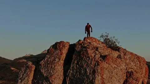 A Man Sits On Top Of A Mountain Which Is Illuminated By The Last Rays Of The Sun Stock Footage 150592216