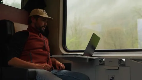 A Man Sits on a Train, Working on His Laptop, Looking Overwhelmed and Stressed Stock Footage 333795771