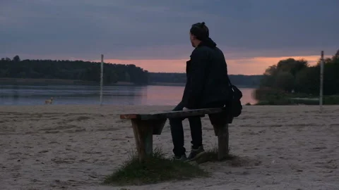 Man sits upon bench and watching sunset, back view Stock Footage 162464528