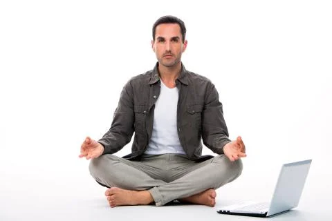 Man sitted on the floor looking at the camera and practicing yoga with laptop Stock Photos