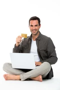 Man sitted on the floor, smiling at camera, showing credit card and buying on Stock Photos