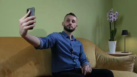 Man sittin on the sofa at home making selfie with smartphone. Stock Footage 170954039