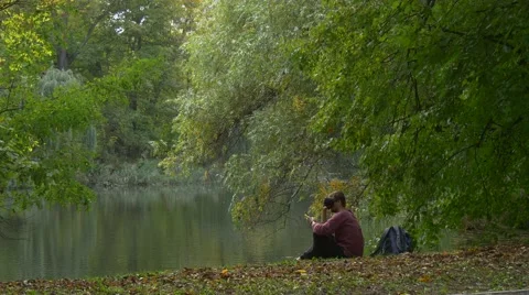 Man Sitting in 360Vr Glasses at the River Bank Nature in Cloudy Day Park by the Stock Footage 68597800