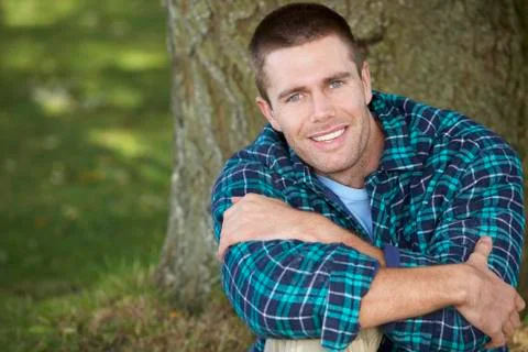 Man sitting against tree trunk Stock Photos