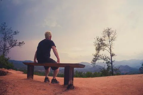 Man sitting alone on bench looking at sunset view Stock-Fotos