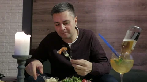 A man is sitting alone in a cafe and enjoying a seafood salad. Salad with Lasso Stock Footage 108595922