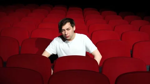 Man sitting alone in empty cinema hall or theater Stock Footage 112228774