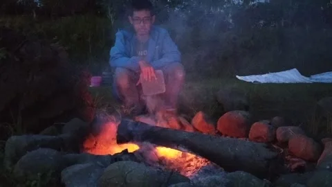 A man sitting alone in front of campfire bonfire at indonesian family fun campin Video stock 151302473