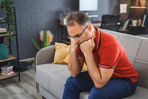 Man sitting alone at home looking sad and distraught Stock Photos