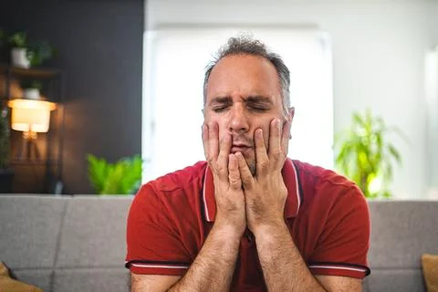 Man sitting alone at home looking sad and distraught Stock Photos