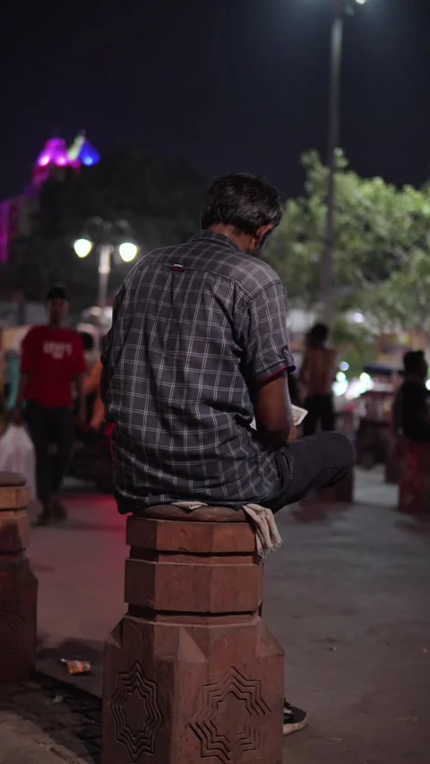 Man Sitting Alone on a Large Concrete Block at a Busy Urban Street Market a.. Stock Footage 345363595