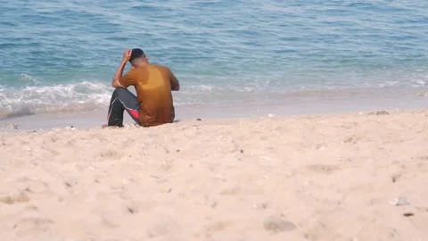 Man Sitting Alone on Sandy Beach Stock Footage 339551539