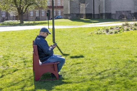 Man sitting alone using smartphone in park with modern lifestyle concept. Stock Photos