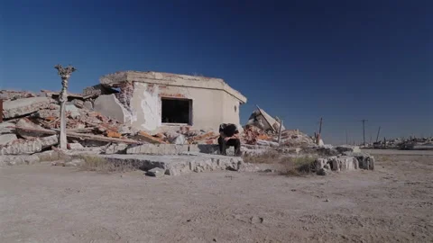 Man sitting among salt covered ruins of Villa Epecuen after the flood Stock Footage 337623906