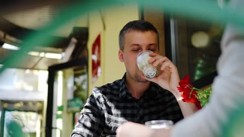A man is sitting and drinking coffee on the street near a cafe Stock Footage 311443935