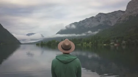 Man sitting and looking at view of mountain lake Grundlsee in fog Stock Footage 132060396