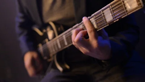 Man is sitting and playing the guitar in a dark room Stock Footage 74126751