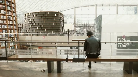 Man sitting and reading a book at the library. Shot from the back. Stock Footage 105423369