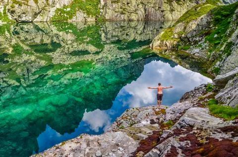 Man sitting and rest on the green moose near by lake in mountains - tatras, s Stock Photos