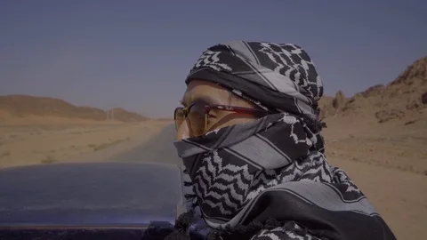 Man sitting in the back of a moving hilux in desert Video stock 102778972