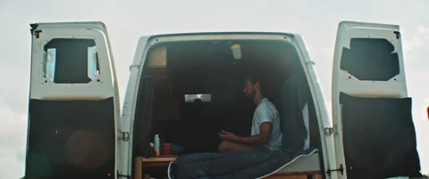 Man sitting in back of a van meditating Stock Footage 203584995