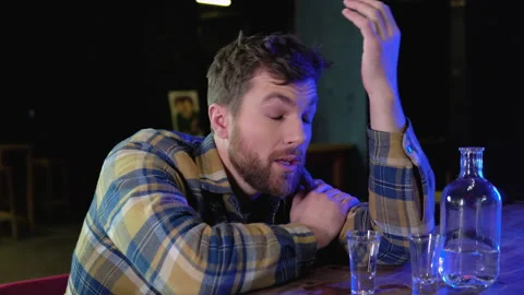 A man sitting at a bar drinking shots or vodka. Drinking, going out, inclusivity Stock Footage 231681979