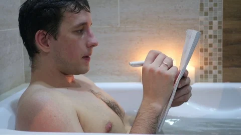 Man sitting in the bathroom with a notebook in hand, crossed out from the list Stock Footage 71459357