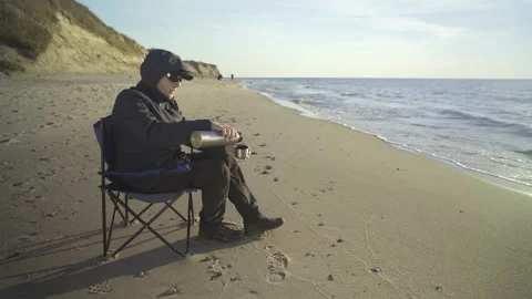 Man sitting on the beach and drinking tea. Stock Footage 239893559