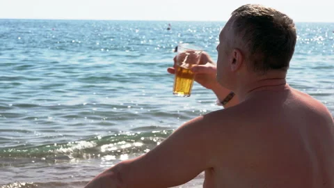 Man sitting on a beach enjoying a cold beer Stock Footage 158926382