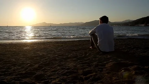 The man is sitting on the beach Stock Footage 81017466