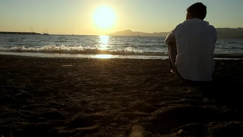 The man is sitting on the beach Stock Footage 81017492