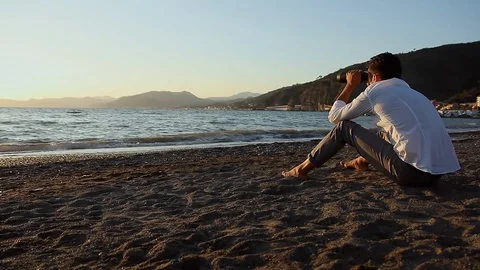 The man is sitting on the beach Stock Footage 81017514