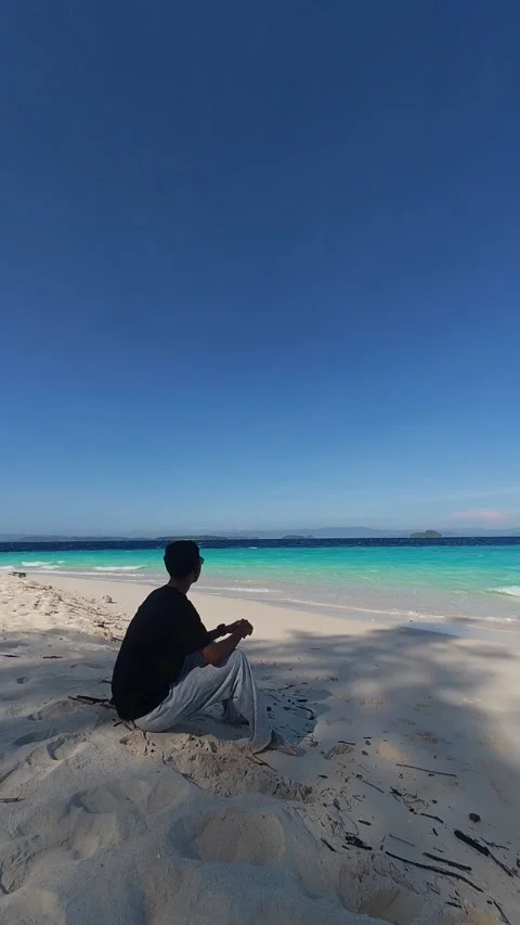Man Sitting on Beach Looking at Ocean Stock Footage 338371366